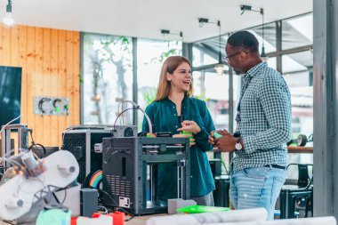 İki ürün tasarımcısı tasarım stüdyosunda 3 boyutlu prototipleri inceleyip tartışıyor. Ürün geliştirmede katkı sağlayan üretim teknolojisi kullanılarak takım çalışmasını, yaratıcılığı ve uygulamalı testleri vurgulamak