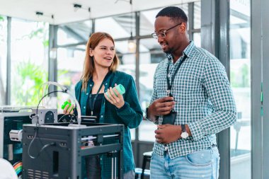 İki ürün tasarımcısı tasarım stüdyosunda 3 boyutlu prototipleri inceleyip tartışıyor. Ürün geliştirmede katkı sağlayan üretim teknolojisi kullanılarak takım çalışmasını, yaratıcılığı ve uygulamalı testleri vurgulamak