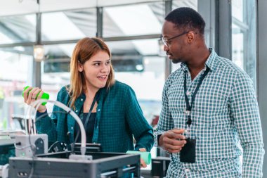İki ürün tasarımcısı tasarım stüdyosunda 3 boyutlu prototipleri inceleyip tartışıyor. Ürün geliştirmede katkı sağlayan üretim teknolojisi kullanılarak takım çalışmasını, yaratıcılığı ve uygulamalı testleri vurgulamak