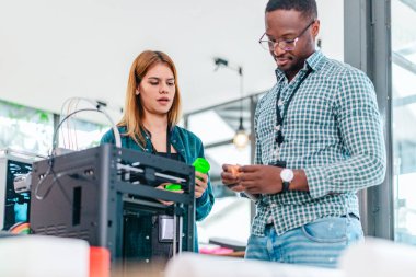 İki ürün tasarımcısı tasarım stüdyosunda 3 boyutlu prototipleri inceleyip tartışıyor. Ürün geliştirmede katkı sağlayan üretim teknolojisi kullanılarak takım çalışmasını, yaratıcılığı ve uygulamalı testleri vurgulamak