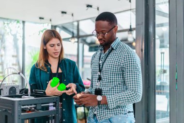 İki ürün tasarımcısı tasarım stüdyosunda 3 boyutlu prototipleri inceleyip tartışıyor. Ürün geliştirmede katkı sağlayan üretim teknolojisi kullanılarak takım çalışmasını, yaratıcılığı ve uygulamalı testleri vurgulamak