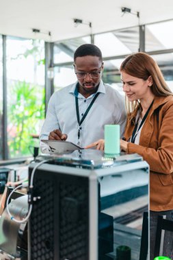 İki ürün tasarımcısı tasarım stüdyosunda 3 boyutlu prototipleri inceleyip tartışıyor. Ürün geliştirmede katkı sağlayan üretim teknolojisi kullanılarak takım çalışmasını, yaratıcılığı ve uygulamalı testleri vurgulamak