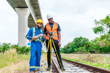 Mühendis ve saha teknisyeni, demiryolu boyunca hassas ölçümler yapmak için tripod takılı lazer metre kullanıyor. Düşük karbon için modern demiryolu altyapısı gelişimi, sıfır emisyon taşımacılığı