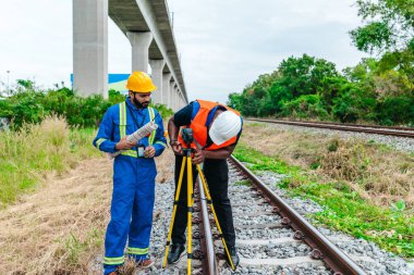 Mühendis ve saha teknisyeni, demiryolu boyunca hassas ölçümler yapmak için tripod takılı lazer metre kullanıyor. Düşük karbon için modern demiryolu altyapısı gelişimi, sıfır emisyon taşımacılığı