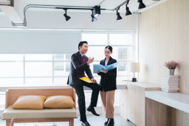 İki profesyonel odaklanmış bir beyin fırtınası oturumunda, planlama araçlarını kullanarak ve tartışarak şık, işbirlikçi bir ofis ortamında yeni fikirler geliştiriyorlar..