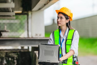 Kadın bir saha analisti pompa istasyonunda inceleme ve veri toplama yapar. Kamu hizmetleri altyapı yönetiminde teknik alan çalışması, kalite kontrolü ve karbon ayak izi denetimi.