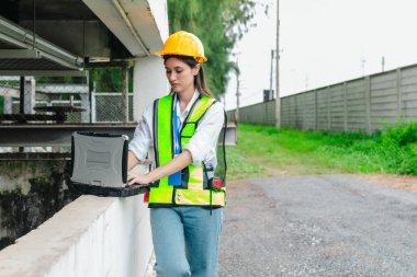 Kadın bir saha analisti pompa istasyonunda inceleme ve veri toplama yapar. Kamu hizmetleri altyapı yönetiminde teknik alan çalışması, kalite kontrolü ve karbon ayak izi denetimi.