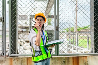 Kadın bir saha analisti pompa istasyonunda inceleme ve veri toplama yapar. Kamu hizmetleri altyapı yönetiminde teknik alan çalışması, kalite kontrolü ve karbon ayak izi denetimi.