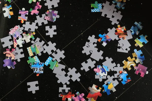 jigsaw puzzle pieces put together on a black background, waiting to be assembled