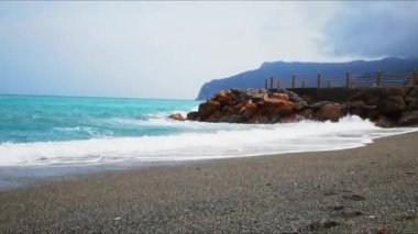 Liguria, İtalya 'nın kumlu sahillerinde köpüğü kopan fırtınalı deniz dalgalarının videosu.