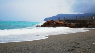 Batı Liguria 'daki bir plajın kayalıklarında deniz dalgalarının 4k videosu.