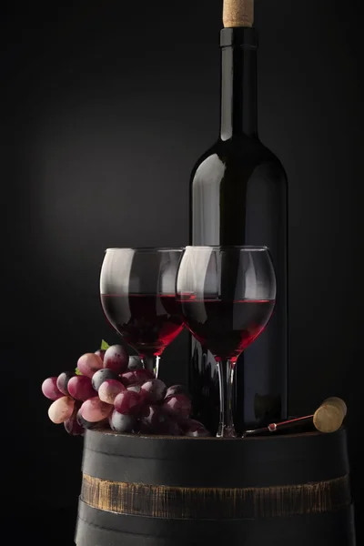 Copo com vinho tinto, videira e velho, barril de madeira isolado em gradiente preto — Fotografia de Stock