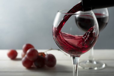 Sarmaşığın yanında iki kadeh kırmızı şarap. Bardaklar şişeden dökülüyor. .