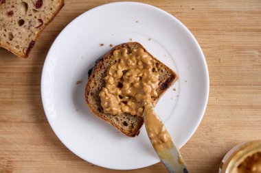 Tabağında fıstık ezmesi olan tahıllı ekmek diliminin üst görüntüsü.