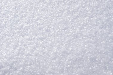 Taze beyaz kar yüzeyini görünür buz kristalleriyle kapatın. Yumuşak ışık ve ince tanecikli doğal kış dokusu.