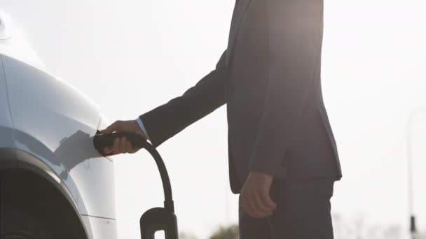 Un hombre de negocios irreconocible desenchufando un coche eléctrico. Lujo coche eléctrico blanco completo. El llenado de energía eléctrica compite y el cable se desconecta. Ahorre energía alternativa ecológica sostenible del futuro — Vídeos de Stock