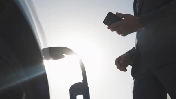 Empresário desligando carro elétrico da estação de carregamento. Luxo carro elétrico branco cheio. Desconectar o cabo quando o enchimento de energia elétrica competir. — Vídeo de Stock