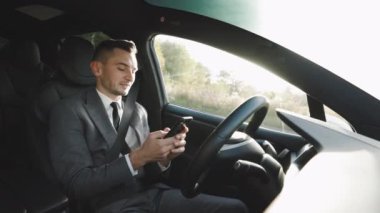 Otoyolda kendi kendine giden akıllı bir araba sürmek için beyaz bir adam tecrübesi. Sürücü, arabada otururken akıllı telefon kullanıyor. İnsanlar ve sosyal medya. Şoför bey. İnsanlar