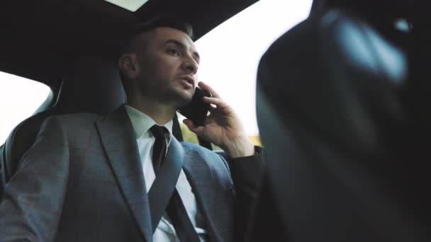 Конфідент Бізнесмен розмовляє на своєму розумовому телефоні під час подорожі на автомобілі бізнес-класу. Красивий кавказький чоловік у своєму Elegant Expensive Car під час їзди з власним водієм. Успішне життя — стокове відео