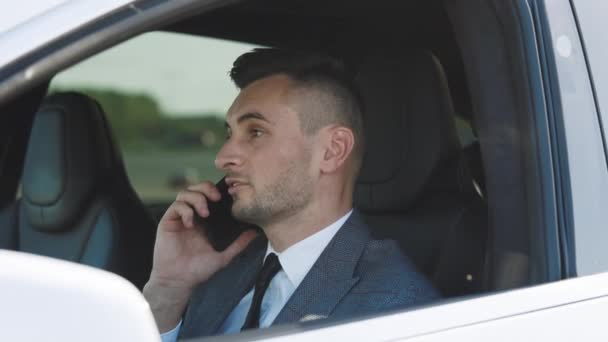 Bellissimo autista uomo che parla al telefono, avendo conversazione con lo smartphone. Un giovane uomo d'affari che parla al cellulare in macchina. Stile di vita, strada, concetto di auto. — Video Stock