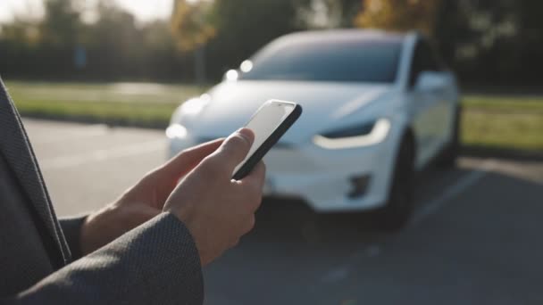 Person controls a self-driving electric car using mobile application. Autonomous autopilot driverless car. Smartphone app. Sensor scanning road ahead for vehicles, danger, speed limits. — Stock Video
