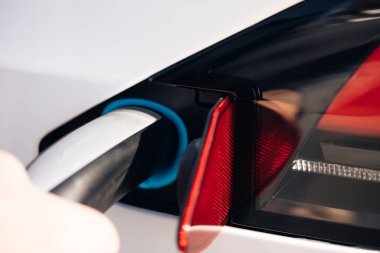 Elektrikli araba şarj kablosu bağlantısını kes. Elektrikli arabanın fişini çeken tanınmayan bir adam. Elektrik güç doldurma yarışması ve kablo bağlantısı kesildi