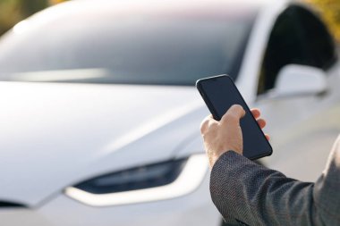Mobil uygulama kullanarak otomatik çalışan bir elektrikli arabayı kontrol eden kişi. Otonom otomatik pilot sürücüsüz araba. Akıllı telefon uygulaması. Algılayıcı tarama yolu ileride araçlar için, tehlike, hız limitleri.