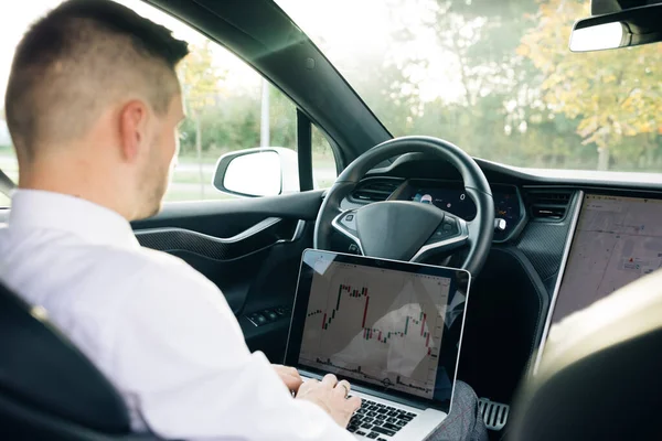 Empresário bem sucedido em roupa formal abrindo laptop pessoal enquanto sentado em carro moderno. Homem barbudo usando computador sem fio no carro. Mercado de ações, negociação online — Fotografia de Stock