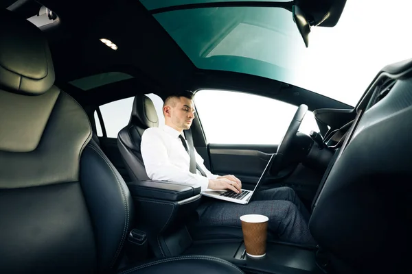 Självkörande elbil autopilot kräver förarens uppmärksamhet att hålla ratten och ta kontroll på motorvägen. Affärsman som arbetar på bärbar dator vid solnedgången. — Stockfoto