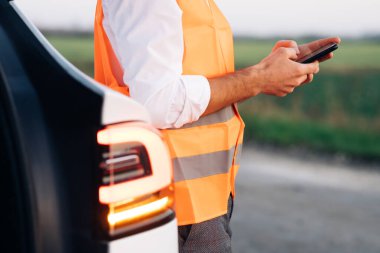 Elektrikli araba bozulduktan sonra telefonu kullanan adam. Flaşlı araba mı yoksa acil durum lambası mı? Elektrikli araba bir kaza geçirdi. Araba servisi.