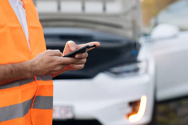 O homem usa o telefone depois do carro eléctrico avariar. Luz da cintilação do carro ou luz de emergência. O carro eléctrico teve um acidente. Serviço de carro — Fotografia de Stock