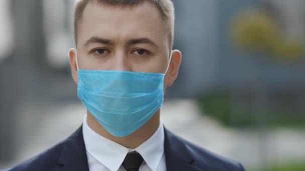 Retrato de um jovem homem de negócios usando máscara protetora na rua. O conceito de saúde e segurança, N1H1 coronavírus quarentena, proteção contra vírus. Vírus pandémico da gripe Corona — Vídeo de Stock