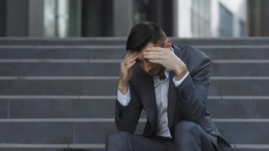 Merdivenlerde oturan mutsuz Avrupalı sakallı adam işinden oldu. Ofis dışında hayal kırıklığına uğramış genç bir iş adamı. İşsizlik parası. Kriz