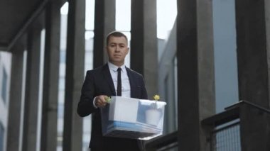Depresyonda olan üzgün erkek ofis çalışanı portresi, kişisel eşyalarla dolu. İş adamı işini kaybetti. Kovulan adam dışarıda. Bunalımlı işsiz insan. İşsizlik kavramı. Parasız kaldı.
