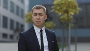 İş dışında duran takım elbiseli yakışıklı bir girişimcinin portresi. Başarılı bir iş adamı. Kurumsal insanlar. Ofis müdürü. İş adamı iş merkezinin yakınındaki kameraya bakıyor.