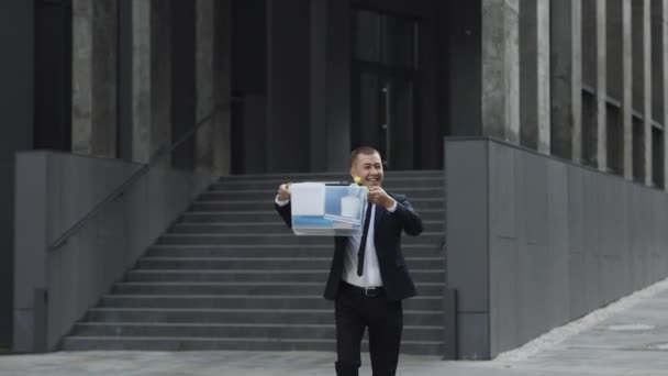 Feliz hombre de negocios caminando por la calle con caja de cosas como salir del centro de negocios y bailar. Trabajador de oficina dejando el trabajo y celebrando. Despedido hombre alegre. Gran día, buen humor — Vídeo de stock