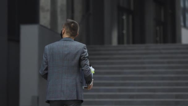 Uomo d'affari in maschera medica torna al lavoro dopo le vacanze. Nuovo impiegato il primo giorno di lavoro che porta la scatola con la roba sul suo nuovo posto di lavoro. Concetto di carriera lavorativa e successo — Video Stock