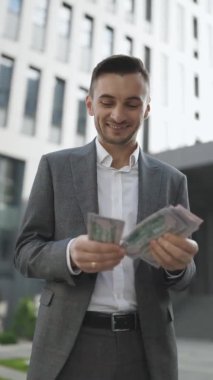 Yakışıklı Zengin Adam Şık Takım Elbise Giyiyor Para Sayıyor Sokakta dikey ofis binasının yanında duruyor