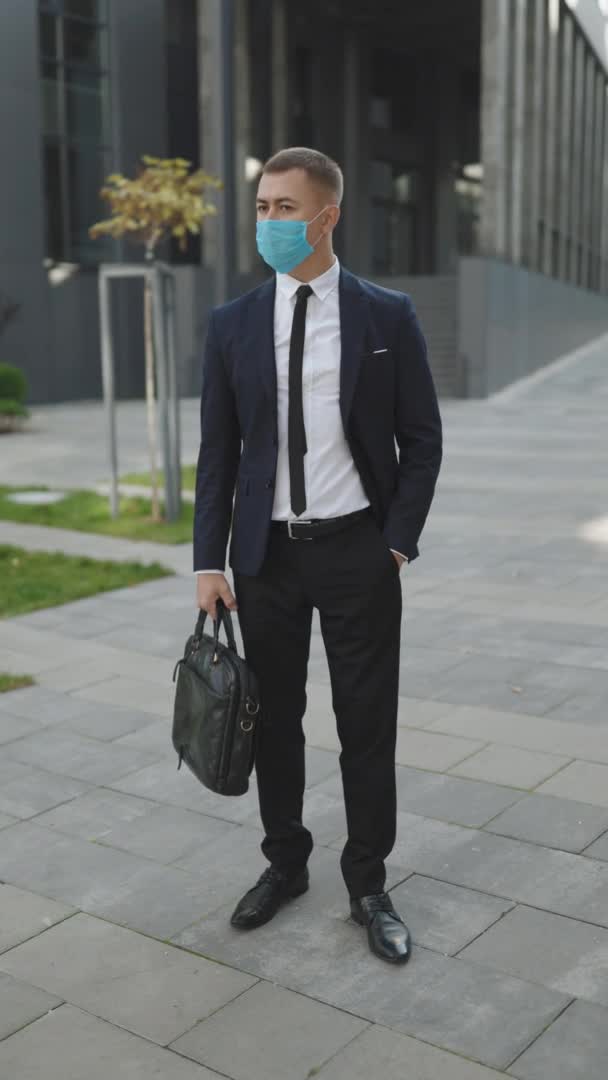 Vídeo vertical de un joven empresario con máscara protectora en la calle. El concepto de salud y seguridad, N1H1 coronavirus cuarentena, protección del virus. Virus de la gripe pandémica Corona — Vídeos de Stock