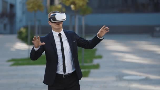 Realidad aumentada. El hombre de negocios toca algo usando gafas 3D vr modernas cerca del edificio de oficinas. Esta nueva tecnología ofrece nuevas dimensiones 3D. Hombre guapo con auriculares de realidad virtual — Vídeos de Stock