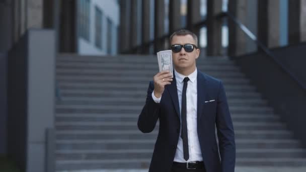 Entreprise prospère ou gagner à la loterie. Pluie d'argent, chute de dollars. Portrait photo de joyeux riche beau homme d'affaires en lunettes et costume jette de l'argent. Joyeux beau homme jetant des dollars — Video