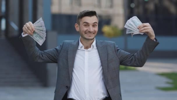 Empresário animado feliz surpreendente com dinheiro notas de dólares da moeda dos EUA. Homem mostra dinheiro e celebrando o sucesso, vitória enquanto olha para a câmera. — Vídeo de Stock
