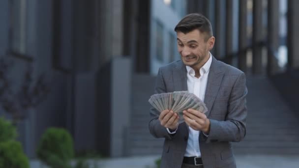 Životní styl, bohatství, radost, úspěch. Šťastný bohatý úspěšný muž drží venku dolary. Portrét spokojeného podnikatele drží peníze — Stock video
