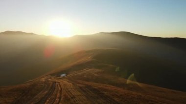 Dağlardaki bulutların arasından yükselen Dağ Havası güneş ışınları. Dağ Menzilli Siluet Günbatımı Hava Görüntüsü. Manzaralı Güneş Işığı Dağları Genel Görünümü