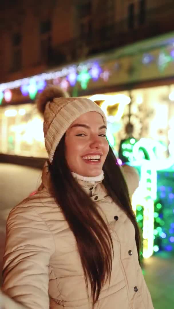 女性ブロガーの垂直ショットは、クリスマスタイムの通りで彼女の社会的なページのために話してビデオを作っています.休暇｜Winter Outlook. — ストック動画