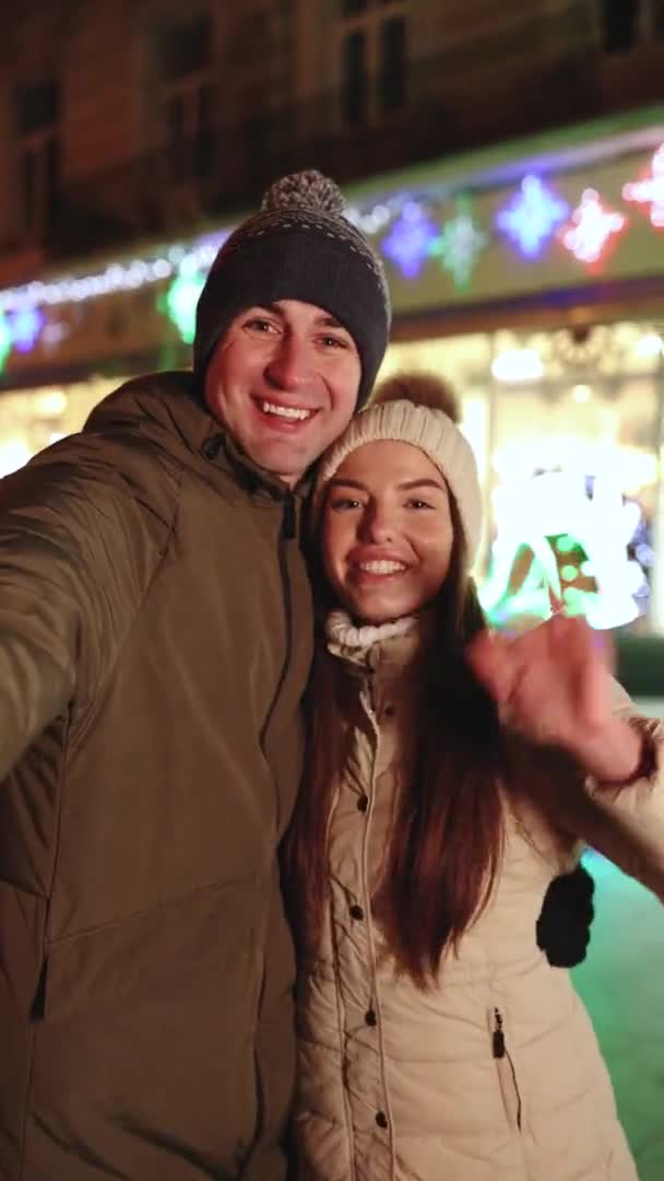 Vertical Shot of Young Couple Bloggers Stands Hugging Making Video Talking for Social Page at the Street in Christmas Time. Dovolená Zimní venkovní. — Stock video