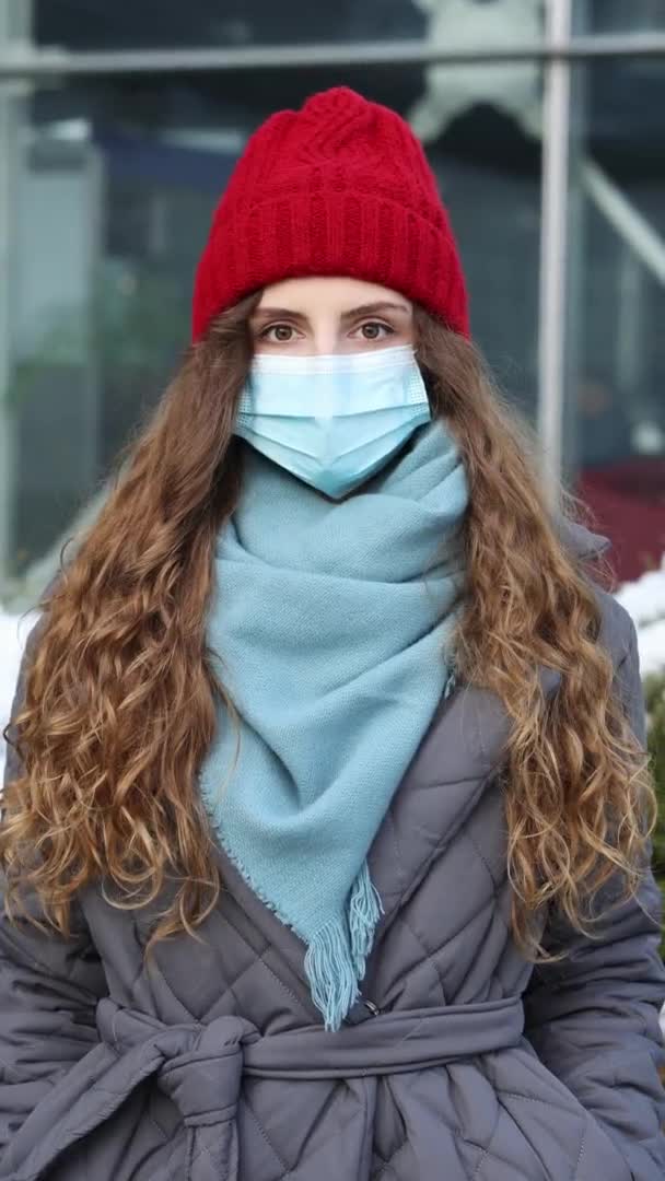 Tiro vertical de retrato de mujer rizada joven caucásica en mascarilla médica de pie en la calle. Multitud de personas enfermas covid-19. Coronavirus epidémico. Virus de la corona pandémica de gripe — Vídeos de Stock