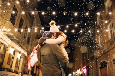 Güzel bir aşk çifti. Aydınlanma. Dışarıdaki mutlu çift. Çekici genç bir kadın, erkek arkadaşıyla Noel partisinde buluşuyor. Sıkıca sarılıyor, sokakta sallanıyor.