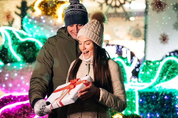 Jonge gelukkige paar verliefd nemen grappige selfies op een smartphone in de kerstsfeer. Kerst versierd. Cadeauwisseling. Kerstcadeau aan mooie vrouw — Stockfoto