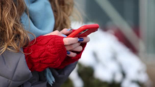 Zbliżenie kobieta ręka smsuję na smartfon, stojąc na ulica w zimowy miasto na nowy rok. Kobiece palce stukające komórką na zewnątrz. Nowoczesne wakacje zakupy online, kupowanie prezentów noworocznych. — Wideo stockowe